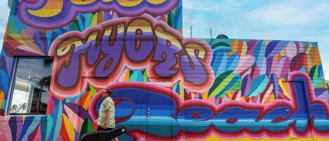 Un mural colorido con texto grande y formas abstractas en la fachada de un edificio.