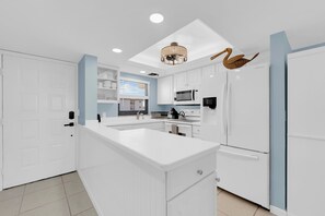 Una cucina moderna con mobili bianchi, un'isola centrale e un forno a microonde integrato.