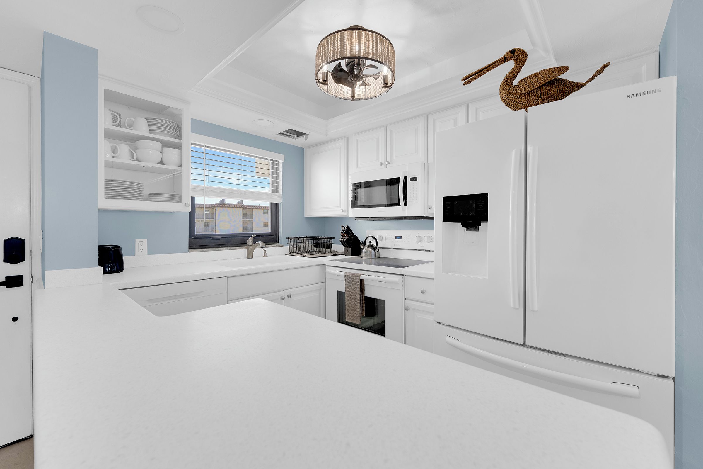 A modern kitchen with white cabinetry, a built-in microwave, and a large refrigerator.
