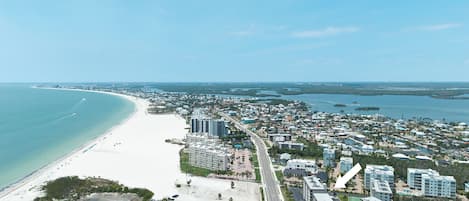 Un paisaje urbano costero con una playa, edificios altos y cielo despejado.