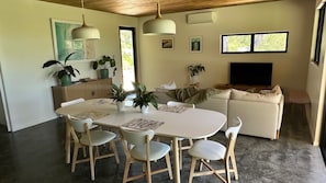 Un espacio habitable moderno con comedor, sofá y televisor.