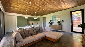 A modern living room with a sectional sofa, a dining area, and a kitchen in the background. - Private coastal villa with traditional sauna located in a beautiful bush setting (Margaret River)
