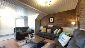 A living room with two sofas, a coffee table, and a brick wall. - Doonloughan View, Ballyconneely (Ballyconneely)