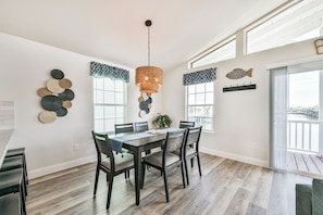 A dining area with a wooden table and chairs, a hanging light fixture, and decorative wall art.