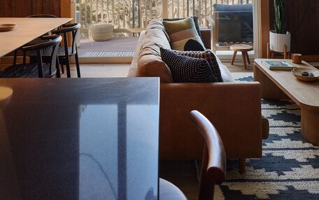 A spacious living room with a large window, wooden ceiling, and a cozy seating area.