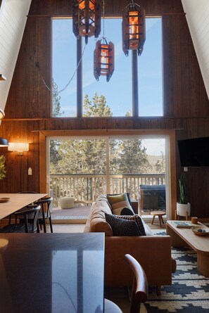 A spacious living room with a large window, wooden ceiling, and a cozy seating area.