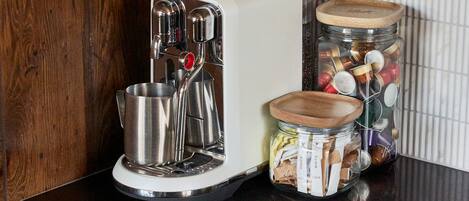 A kitchen with a coffee maker, two jars with lids, and wooden cabinets.