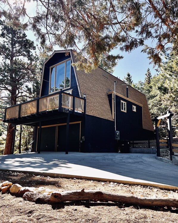 A modern house with a large balcony, a garage, and a clear view of the surrounding forest.