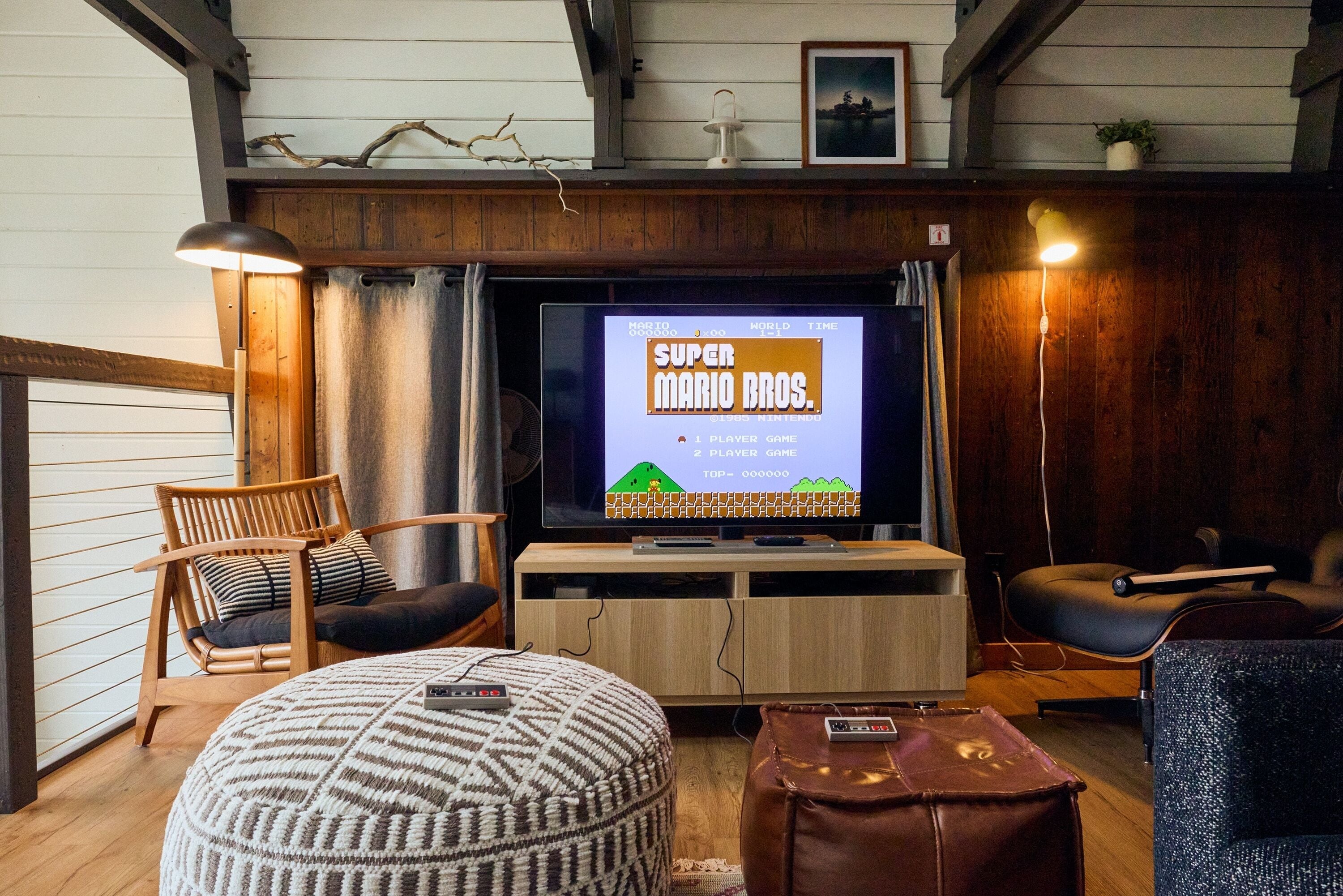 A living room with a television displaying a game, wooden furniture, and a lamp.