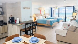 Ein modernes Hotelzimmer mit Küchenzeile, zwei Betten, einem Balkon mit Aussicht und einem Essbereich.