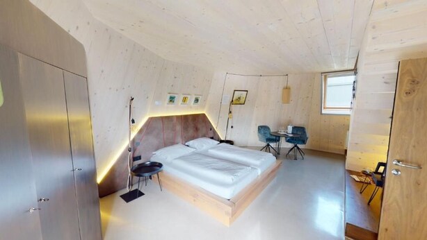 A bedroom with a wooden bed, a desk, and a chair. - Ikuna Naturresort (Natternbach)