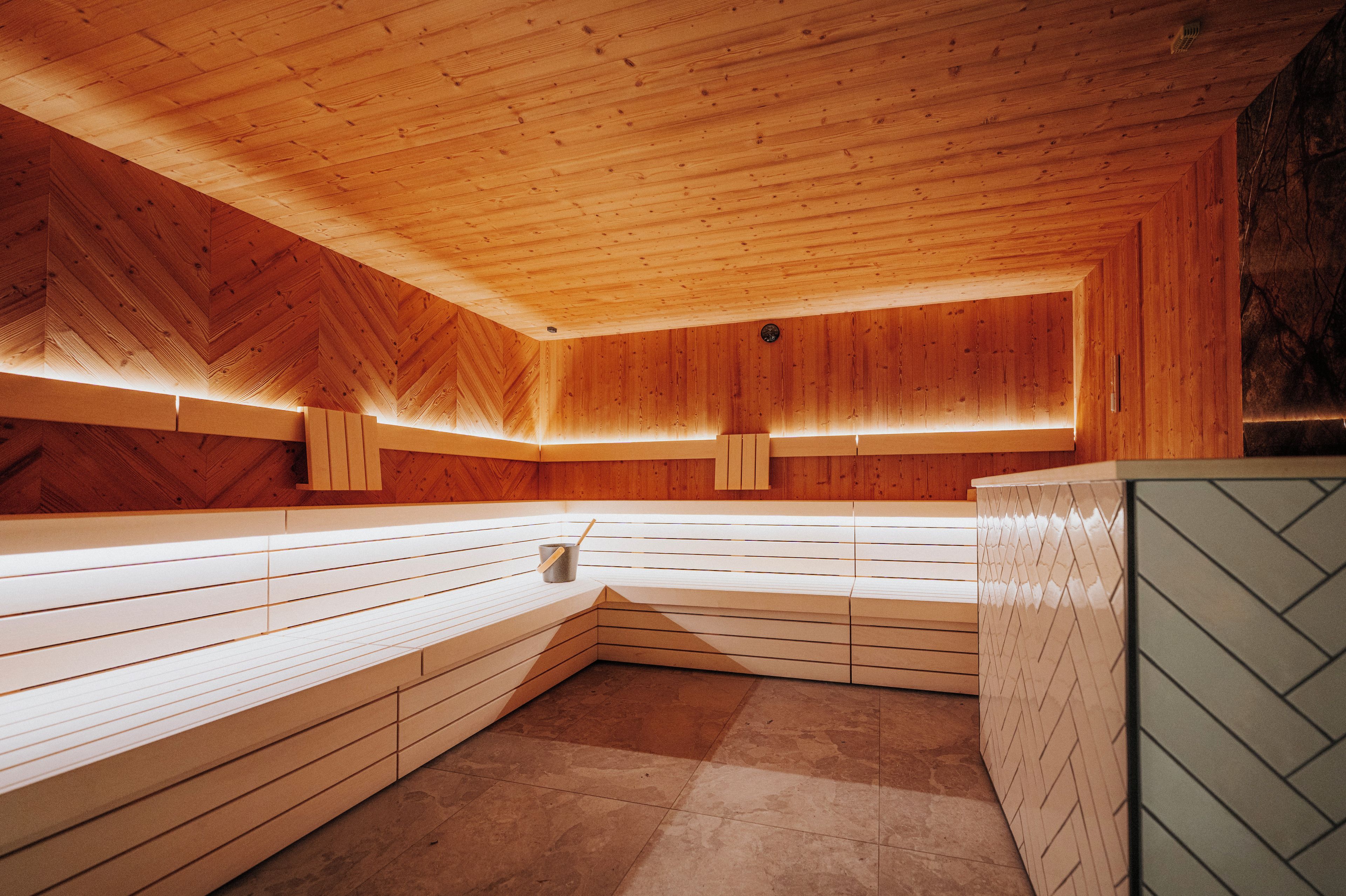 A sauna with wooden benches and a herringbone-patterned wall.