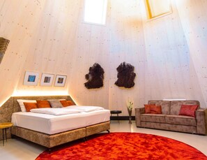 Ein Zimmer mit einem Bett, einem Sofa, einem roten Teppich und zwei gerahmten Bildern an der Wand.