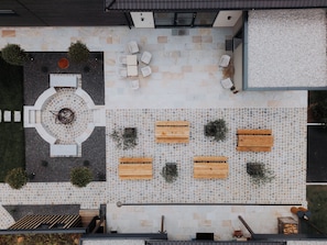 A rooftop terrace with a circular seating area, wooden benches, and a small fire feature. - Ikuna Naturresort (Natternbach)