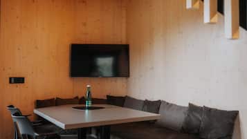 Ein modernes Interieur mit einer Holzwand, einem flachbildfernseher über einem Tisch und einer Couch mit Kissen.