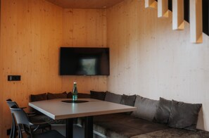 Un interior moderno con una pared de madera, un televisor de pantalla plana sobre una mesa, y un sofá con cojines.
