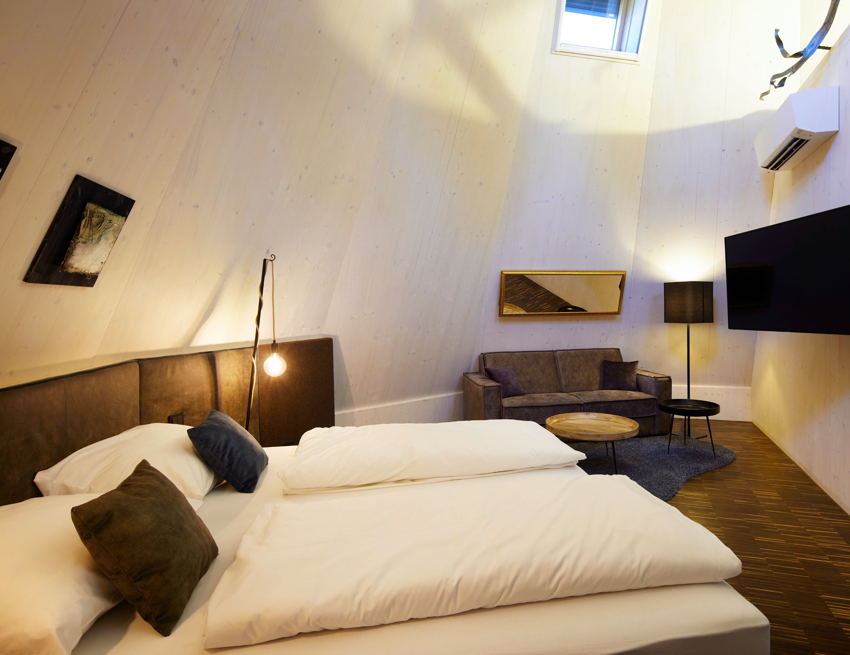 A room with a bed, a sofa, a TV, and a lamp.