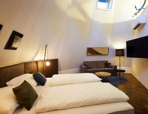 A room with a bed, a sofa, a TV, and a lamp. - Ikuna Naturresort (Natternbach)