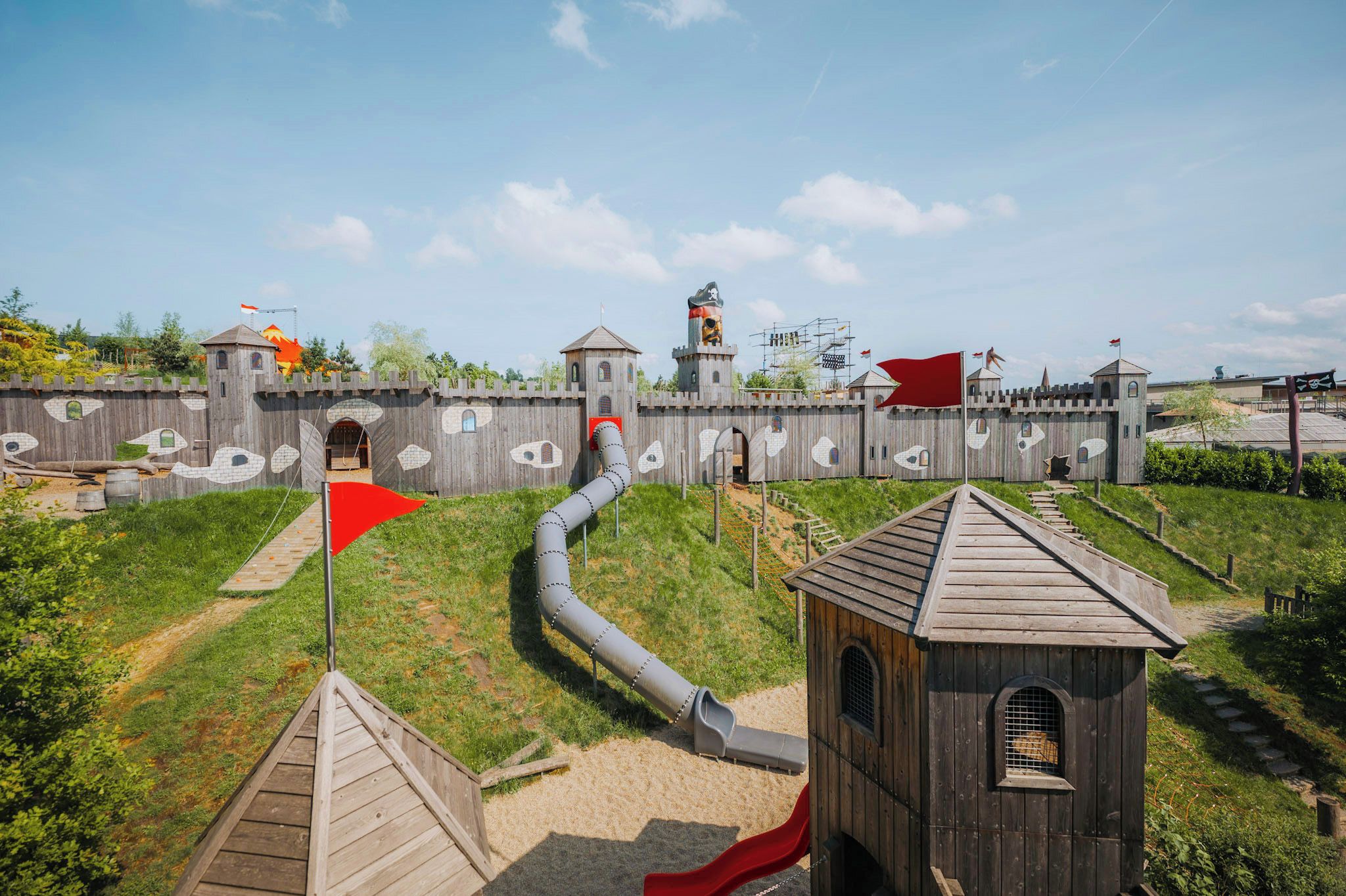 A playground with a slide, a red flag, and a castle-like structure.