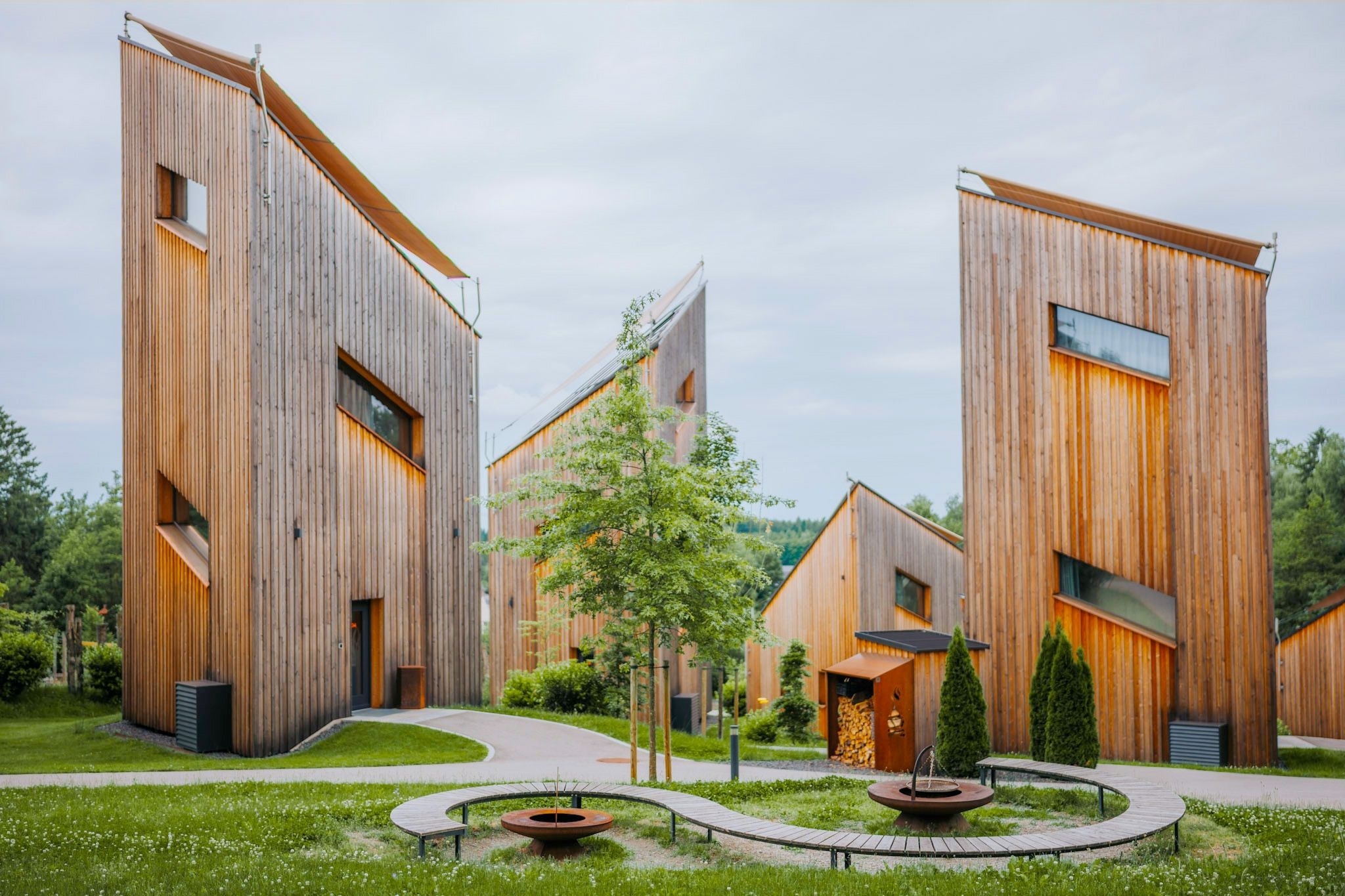 Ein moderner Gebäudekomplex mit einem zentralen Innenhof, umgeben von Holzbauten mit großen Fenstern.