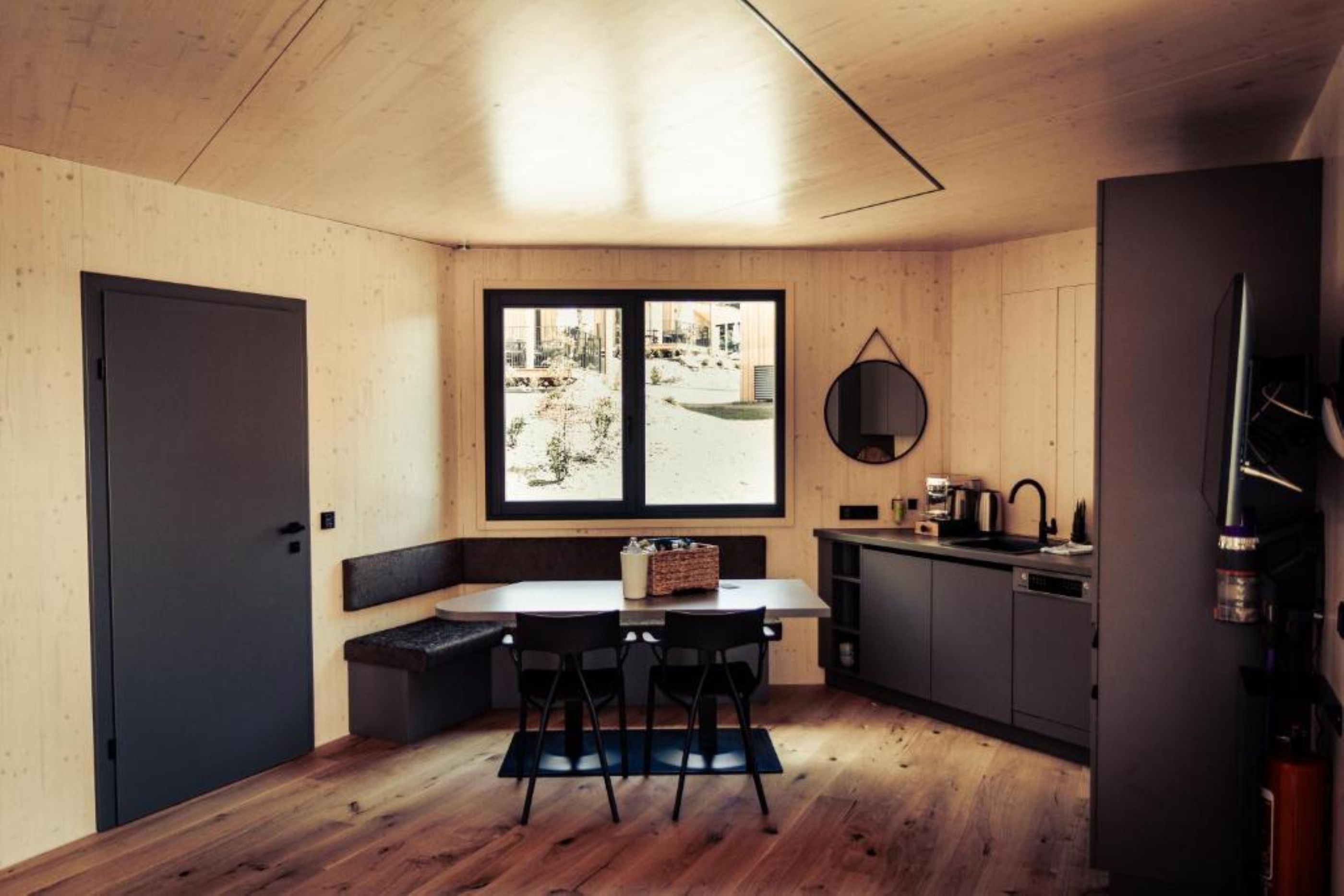 A compact kitchen with a dining table, chairs, a window, and a built-in oven.