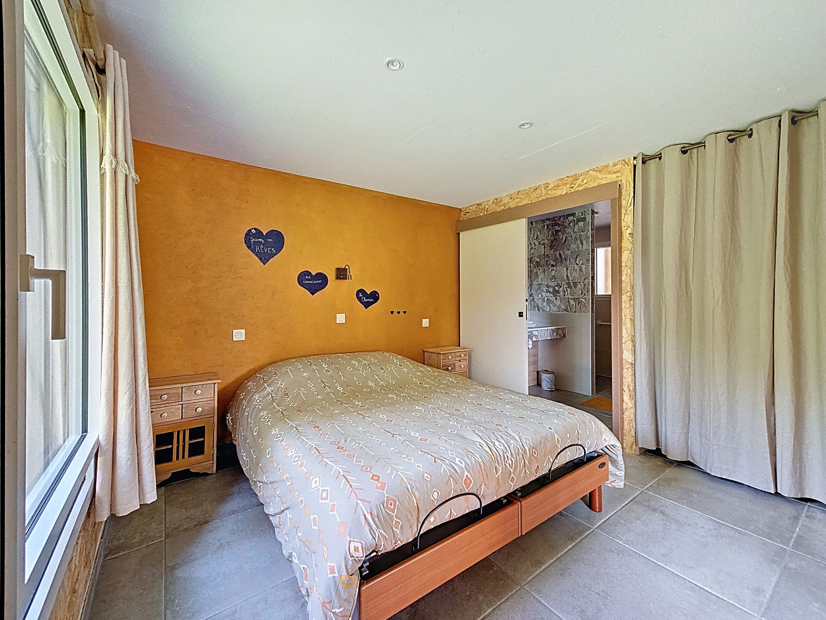 A bedroom with a bed, a dresser, a mirror, and a wall with heart-shaped decorations.