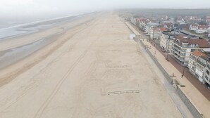 Een strand met een boulevard langs gebouwen met meerdere verdiepingen.