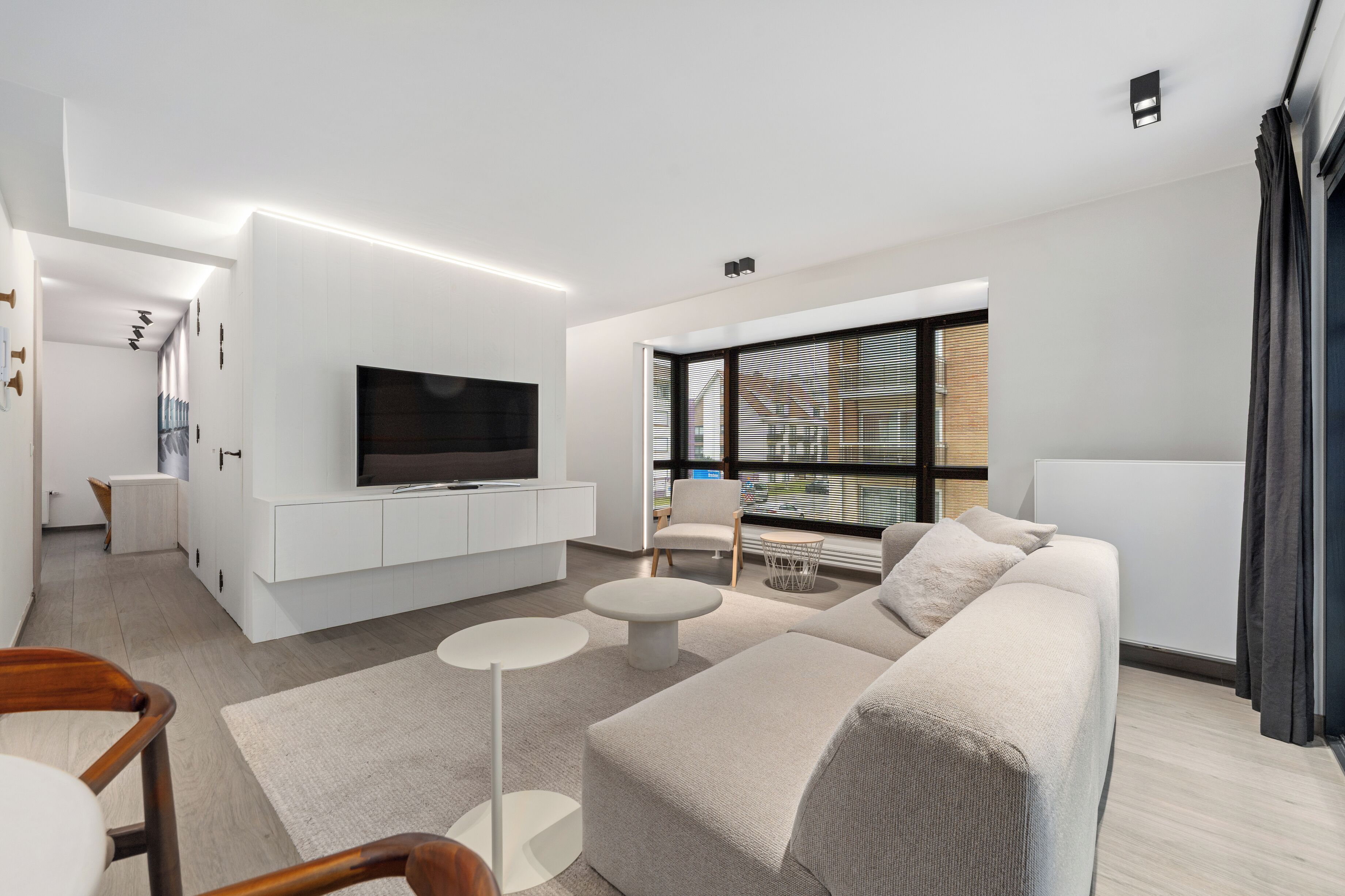 Un salon moderne avec un téléviseur à écran plat, un canapé, une table basse et un fauteuil.