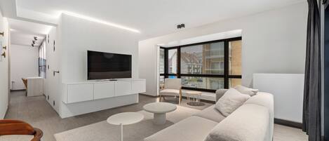 Un salon moderne avec un téléviseur à écran plat, un canapé, une table basse et un fauteuil.