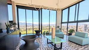 Una sala de estar moderna con un ventanal grande, un suelo estampado y vistas a un paisaje urbano.