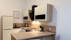 Een moderne keuken met een inbouw-kookeiland, een koelkast, een koffieapparaat en een waterkoker.