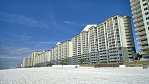 Un hotel sulla spiaggia con diversi edifici a grattacielo, una spiaggia sabbiosa in primo piano e un cielo azzurro limpido.