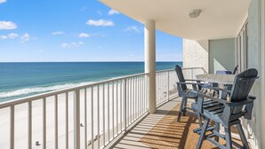 Un balcone con vista sull'oceano, un tavolo con sedie e una ringhiera.