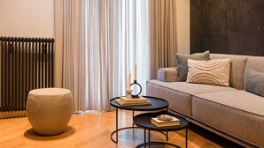 A modern living room with a sofa, ottoman, and a small round table with books and candles. - Bullet Athens (Athina)