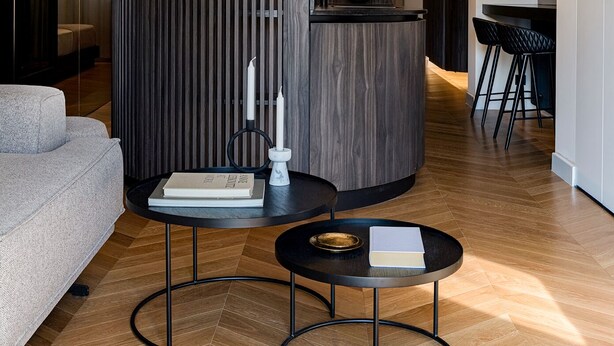 A modern kitchen with a curved wooden accent wall, a built-in sink, and a dining area with a round table and stools. - Bullet Athens (Athina)