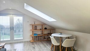 Ein Zimmer mit einem Oberlicht, Holzregalen, einem runden Tisch und zwei Stühlen.