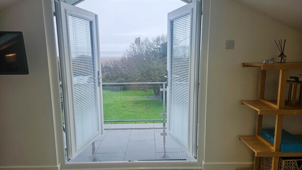 Ein offener Balkon mit Blick auf einen grünen Rasen und Bäume.