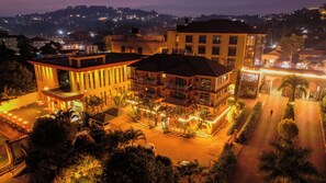 A multi-story hotel with a courtyard, balconies, and a well-lit entrance. - Nican Resort Hotel (Kampala)