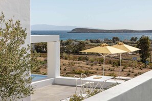 A balcony with a view of the sea, white outdoor furniture, and yellow umbrellas. - Golden Coast Villa Citron Private Wadingpool Gem (Paros)