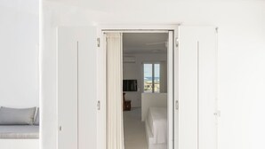A room with a bed, a TV, and a view of the sea. - Golden Coast Villa Citron Private Wadingpool Gem (Paros)