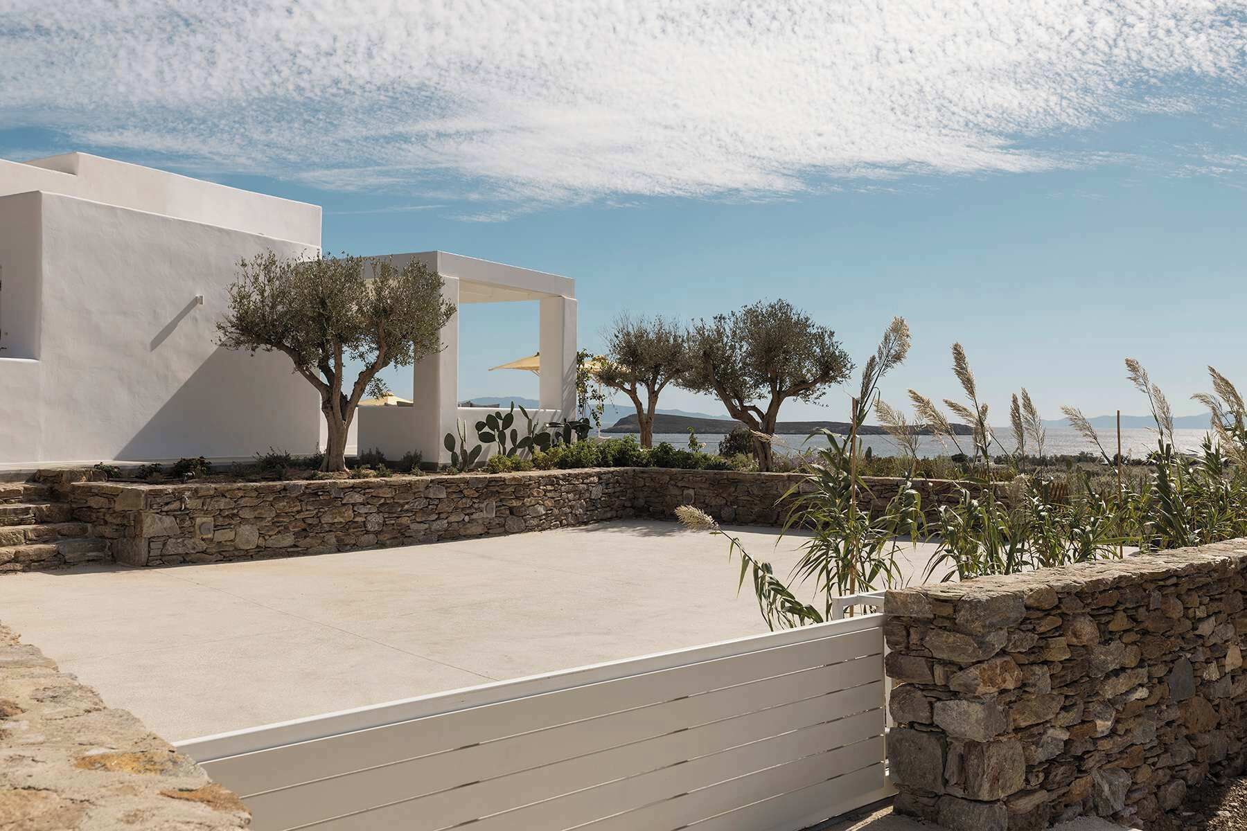 A modern outdoor area with a stone wall, a flat concrete surface, and a white building with a unique architectural design.