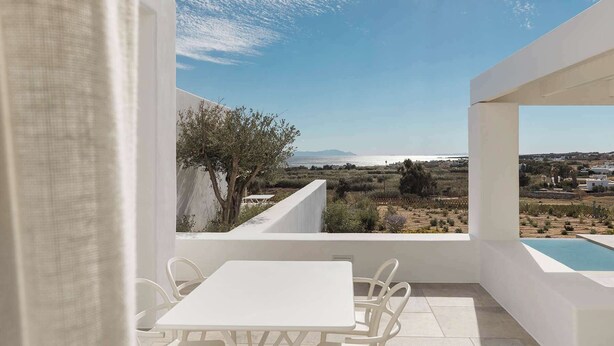 A balcony with a white table and chairs, a pool, and a view of the sea and distant landscape. - Golden Coast Villa Rodi Private Wadingpool Gem in Paros (Paros)