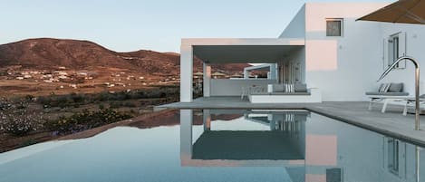 A modern house with a swimming pool, a patio area, and a view of a mountainous landscape.