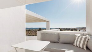 A modern outdoor seating area with a white table and sofa, a pergola, and a clear view of the landscape and sea. - Golden Coast Villa Daphne Private Wadingpool Getaway (Paros)