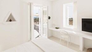 A white room with a bed, a desk, a chair, a TV, and a view through a glass door. - Golden Coast Villa Daphne Private Wadingpool Getaway (Paros)