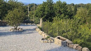 A landscaped garden area with a gravel path, stone borders, and various shrubs. - Aerida Guesthouse Of Stone - Natali Cozy Suite (Rethymno)