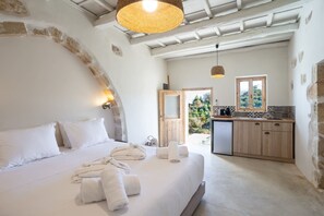 Un dormitorio con cama, toallas, una puerta de madera y vistas al exterior.