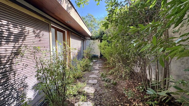 A narrow pathway leading to a building with a sloped roof and a brick exterior. - House Pedro de Valdivia Norte - Garden & Parking (Las Condes)