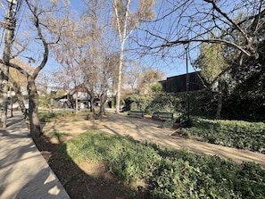 A park with trees, a bench, and a building in the background. - House Pedro de Valdivia Norte - Garden & Parking (Las Condes)