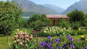 Un jardín con diversas flores y un pequeño edificio de techo rojo.